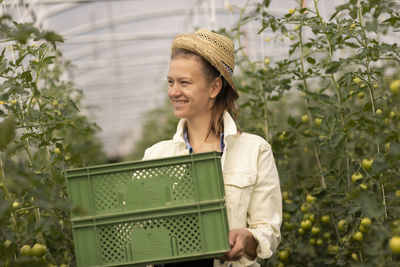 Young woman working as vegetable grower or farmer in a greenhouse