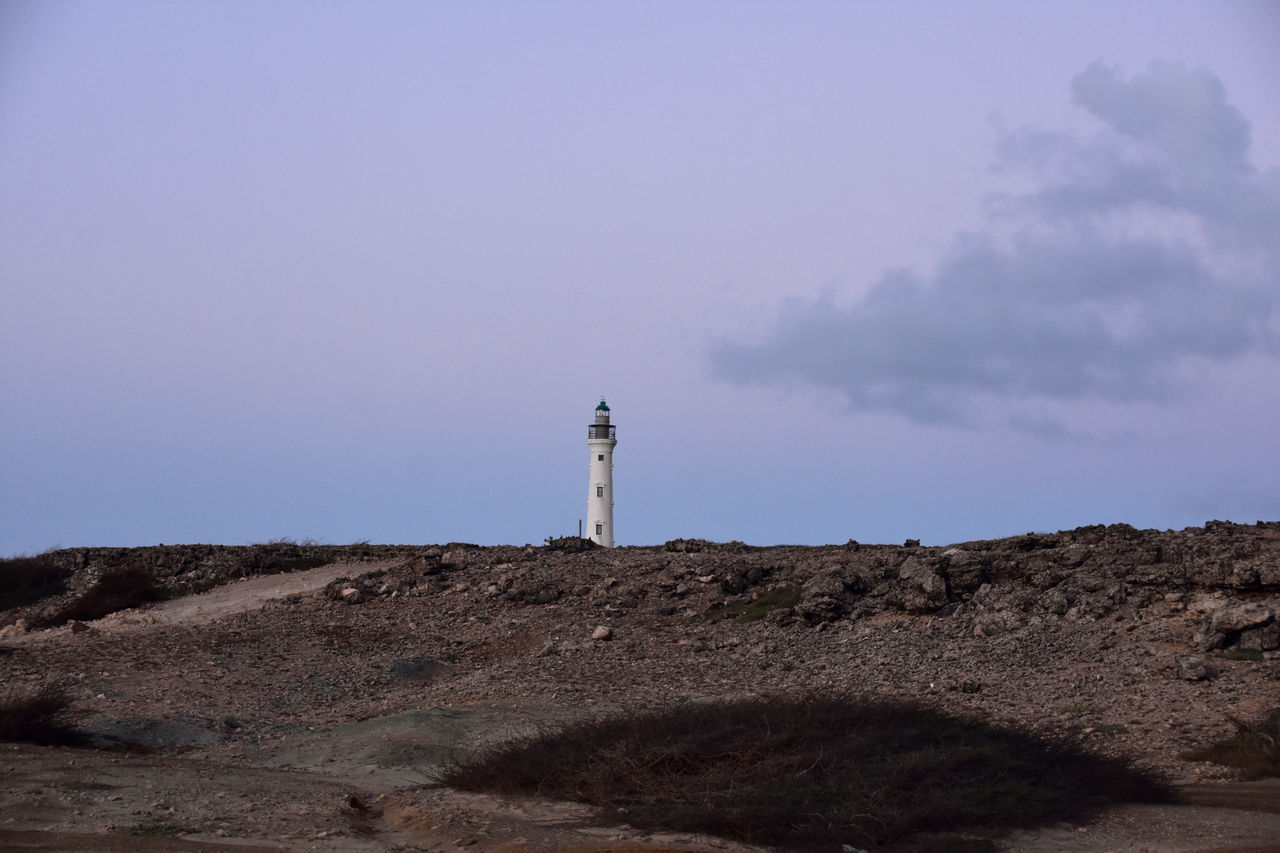 lighthouse, sky, guidance, tower, sea, architecture, built structure, building exterior, nature, coast, land, building, security, protection, environment, hill, landscape, horizon, scenics - nature, travel destinations, rock, travel, cloud, no people, non-urban scene, outdoors, beach, ocean, beauty in nature, day, copy space, tranquility, water, communication