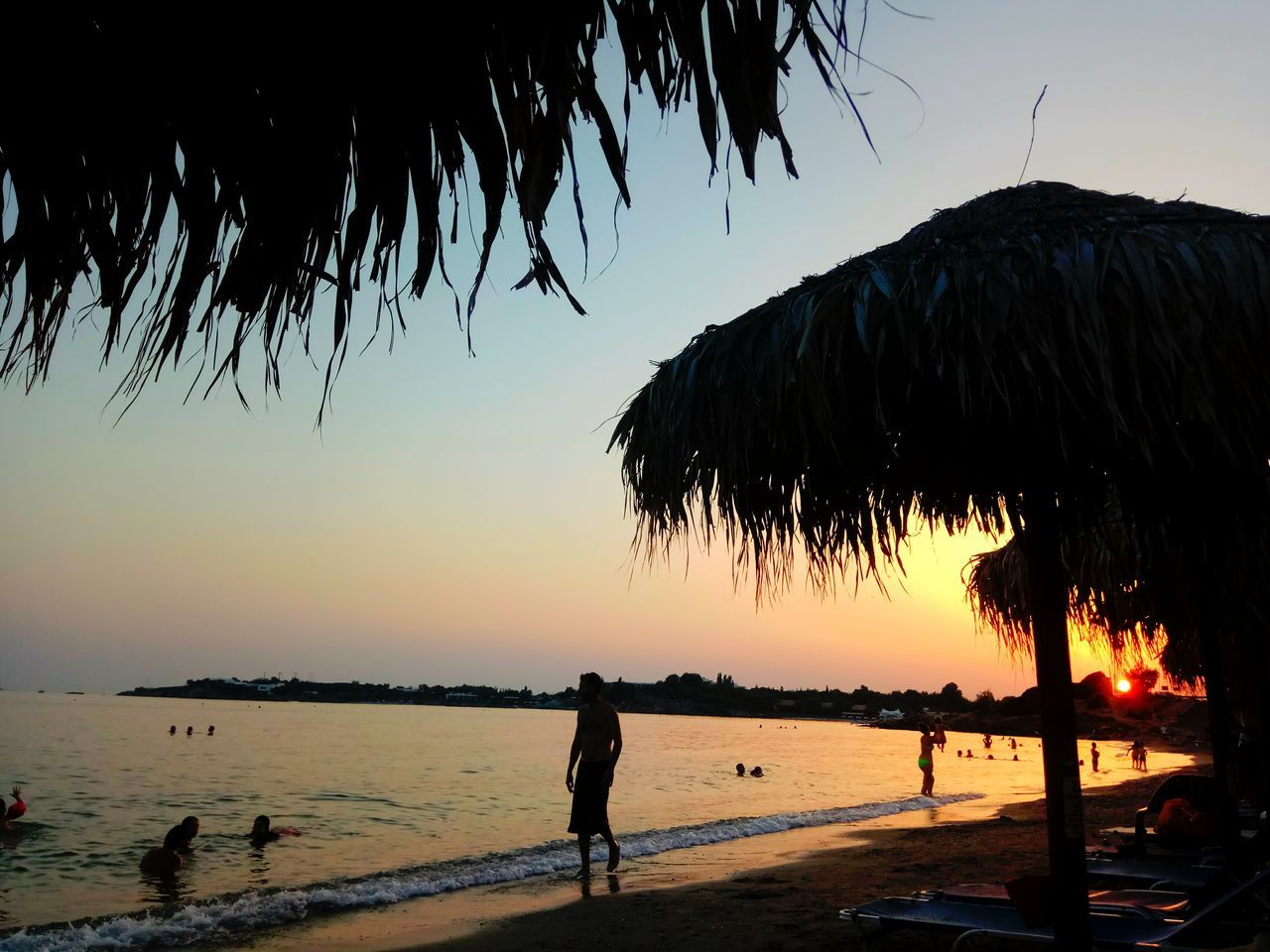 sunset, beach, sea, silhouette, nature, beauty in nature, sky, real people, water, outdoors, scenics, men, standing, tree, clear sky, one person, horizon over water, day, people