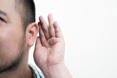 Close-up of mid adult man with hand covering ear against white background