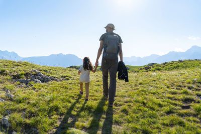 Father and daughter walking on grass during summer