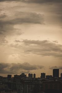 Buildings in city against dramatic sky