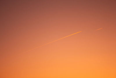 Low angle view of vapor trails in sky during sunset