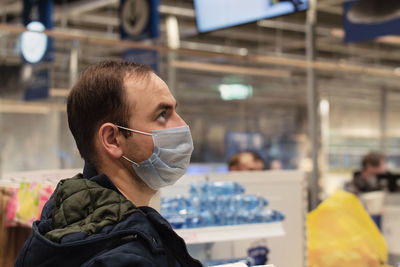 Man in medical face mask looks up. shopping in the store before lockdown or during quarantine.