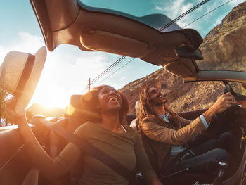 Low angle view of cheerful couple traveling in convertible