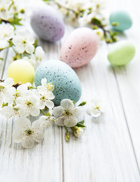 Colorful easter eggs with spring blossom flowers over wooden background. colored egg holiday border.
