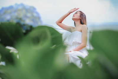 Woman gesturing stop sign while sitting by plants