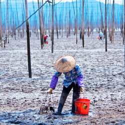 Man with bucket working on muddy field