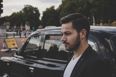 Businessman standing by car in city