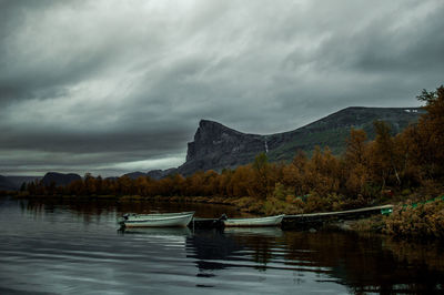 Boats in lake against cloudy sky