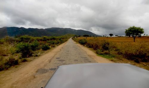 Empty country road against cloudy sky
