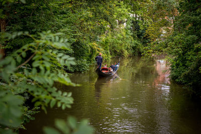 People in gondola on lake amidst trees