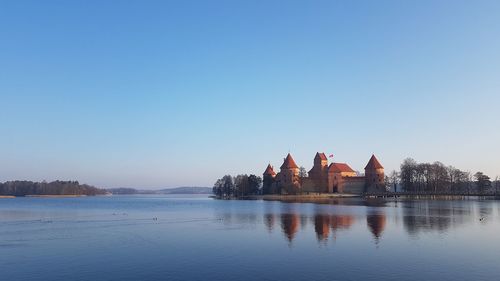 Panoramic view of lake by building against clear blue sky and trakai island castle