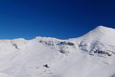 Scenic view of snowcapped mountains against clear blue sky