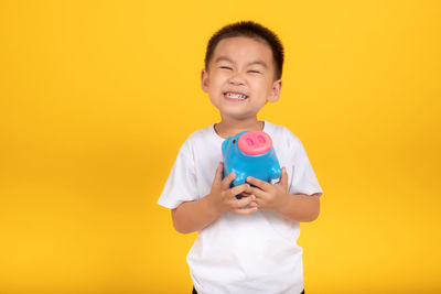 Happy boy standing against yellow background