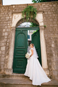 Woman leaning on stone wall of building