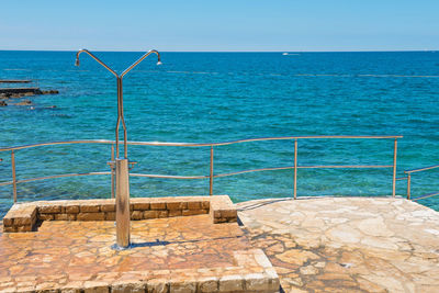 Swimming pool by sea against clear sky
