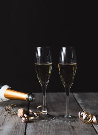 Two glasses of champagne and top of bottle with black background.