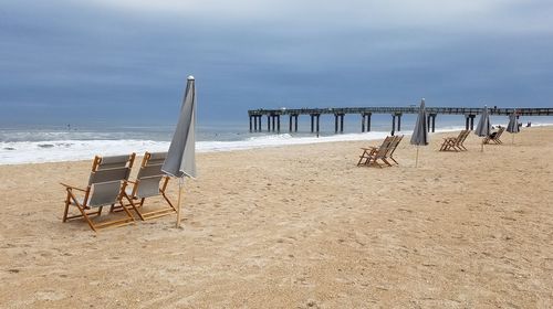 Chairs on beach against sky