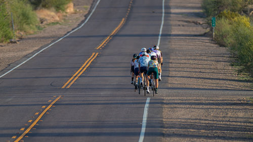People riding bicycles together on road into the distance