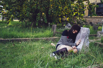 Rear view of woman sitting on grassy field