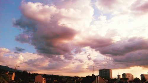 Low angle view of cityscape against cloudy sky