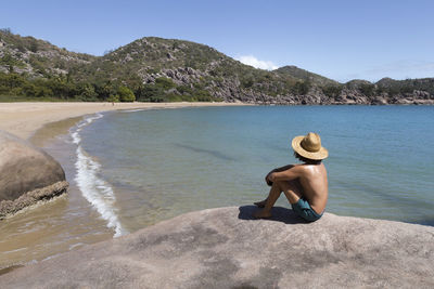 Full length of shirtless man in sea against sky