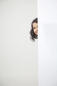 Portrait of smiling woman standing against white wall