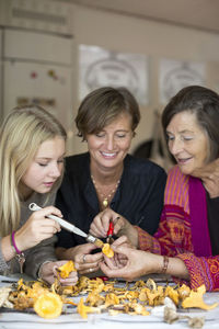 Three generation females cleaning chanterelle mushroom together at home