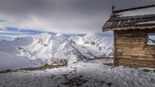 Snow covered houses by mountain against sky