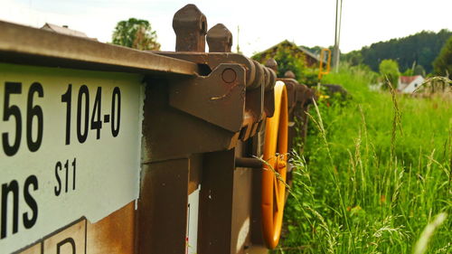 Close-up of information sign on field against sky