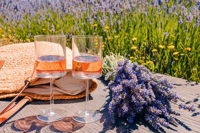 Two glasses of rose wine and bouquet of lavender flowers, summer picnic in countryside