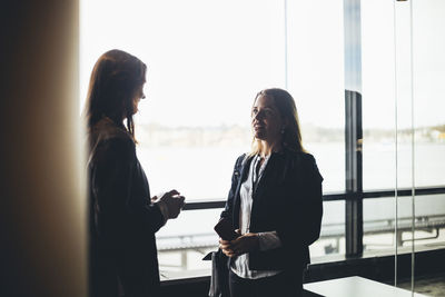 Female colleagues discussing while standing at workplace