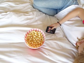 High angle view of woman holding popcorn on bed