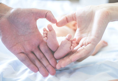 Cropped hands of couple with baby at home