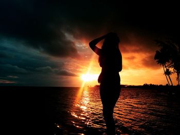 Silhouette woman standing at beach during sunset