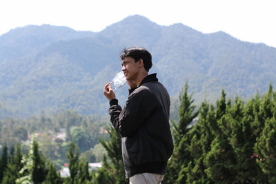 Young man standing against mountains and wear a mask