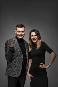 Fashionable couple standing against gray background