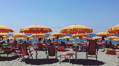 Chairs and parasols on beach against clear blue sky