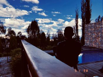 Rear view of silhouette man sitting against sky