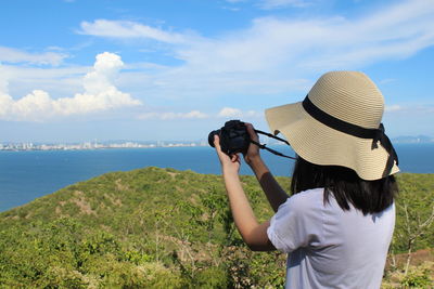 Rear view of woman photographing sea against sky