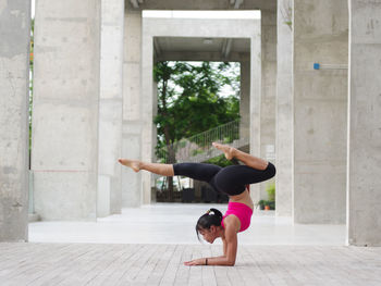 Full length of young woman exercising in colonnade