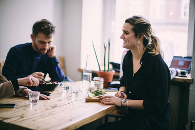 Young woman looking away while sitting on table