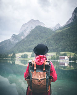 Rear view of boy looking at lake against mountain range