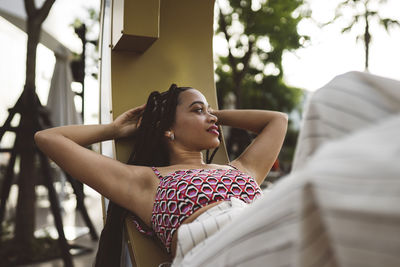 Thoughtful young woman lying with hands behind head