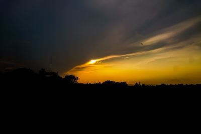 Silhouette landscape against dramatic sky during sunset