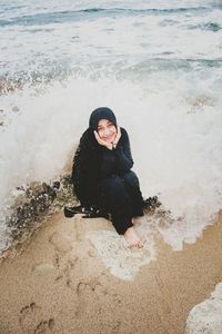 Woman sitting on shore at beach