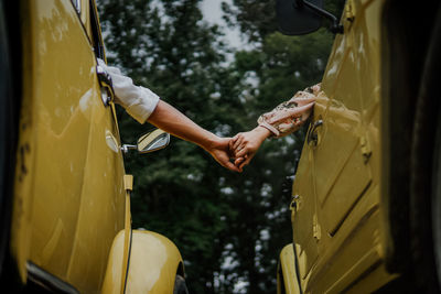 Cropped image of people holding hands while sitting in car