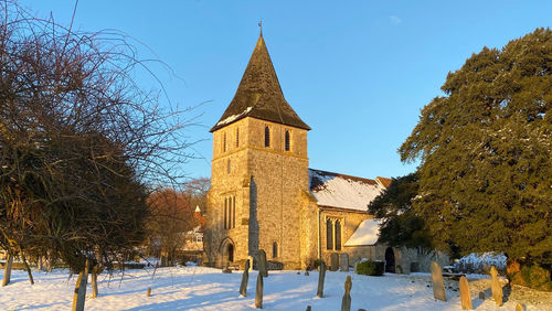 Church amidst trees and buildings against sky during winter