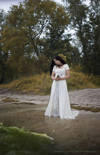 Full length of woman standing against trees